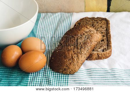 Fresh eggs and slides of brown bread on tablecloth