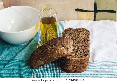 Olive oil and slides of brown bread on tablecloth