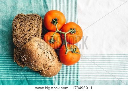 Tomato and slides of brown bread on tablecloth. Top view with space for copy