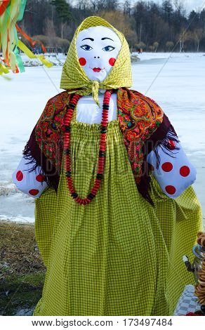 Shrovetide doll in colorful headscarf and sarafan with large beads on neck