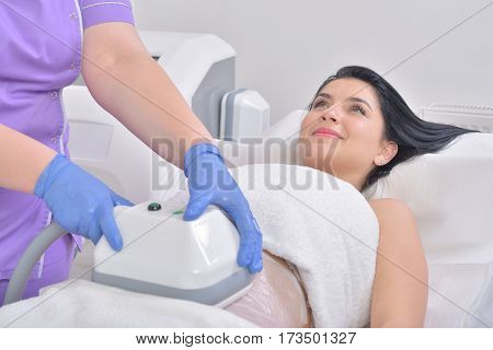 Pretty young woman getting cryolipolyse fat treatment in professional cosmetic cabinet