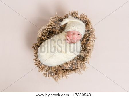 Adorable baby all covered up resting on a big furry brown pillow, topshot