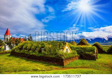Rural pastoral. Church bell tower with red gabled roof and old village. Ethnographic Museum-estate Glaumbaer, Iceland. The concept of the historical and cultural tourism