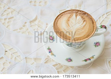 Latte Art Coffee in the vintage cup on the table in the coffee shop