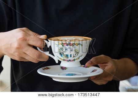 close up of woman hands holding vintage cup of coffee