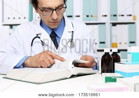 Doctor reading a Medical Book in Office Desktop. Health care Medical and Pharmacy Concept.