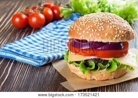 Homemade cheeseburger with beef patties and fresh salad on seasame buns, sered on brown wooden table.
