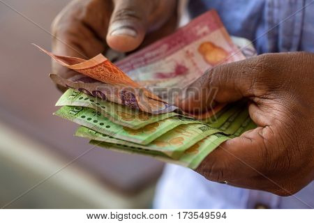 Closeup photograph of hands counting srilankan rupies