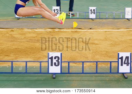 Sportswoman jumping into sandpit on triple jump competition in track and field championship
