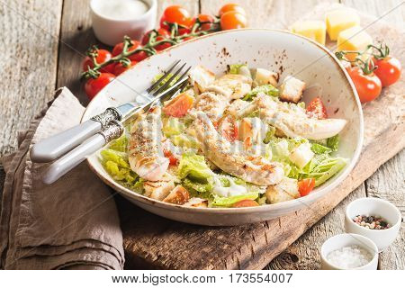 Delicious caesar salad with croutons, grilled chicken breast, grated parmesan cheese and cos lettuce, with sauce in the gravy boat, simply and healthy recipe