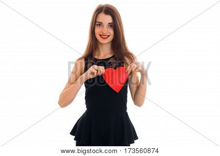 a charming young girl in black dress holding a red heart and smiling isolated on white background