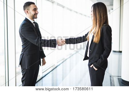 Businessman and Businesswoman handshake in office with big panoramic windows