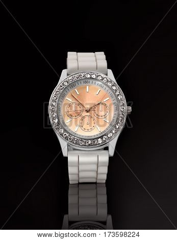 Women's wristwatch with a white strap. On a black background