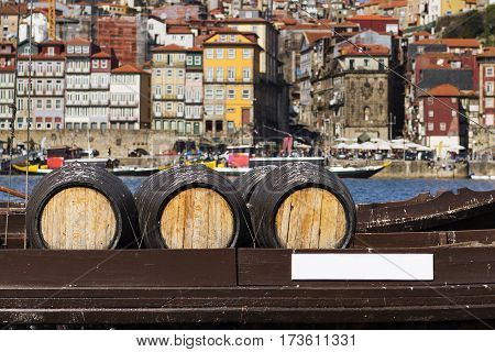 Detail of Port Wine barrels in a boat in the Douro River with the city of Porto in the background