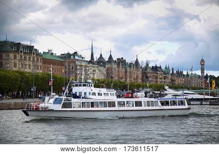 STOCKHOLM SWEDEN - AUGUST 20 2016: Many people walk and visit on Strandvagen street on Ostermalm distric with touristic sightseeing boats in Stockholm Sweden on August 20 2016.