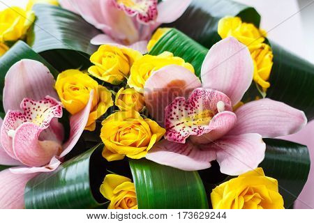 Bright bouquet of fresh pink orchids and yellow roses, floristic composition.