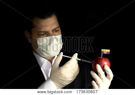 Young Businessman Injecting Chemicals Into An Apple With Ecuadorean Flag On Black Background