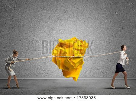 Two businesswomen playing tag of war game