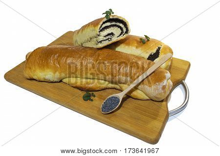 Сut poppy roll baked at home with sprigs of mint on a wooden board with a wooden spoon filled with grains of poppy. Isolated on white background.