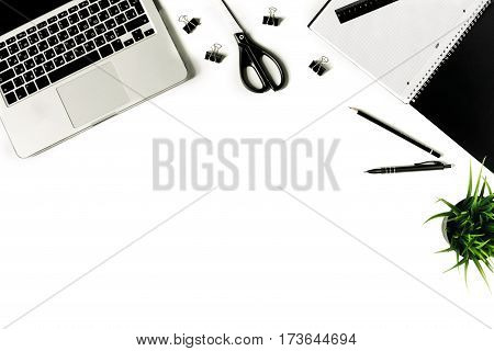 White office desk frame with laptop keyboard and supplies. Laptop, notebook, pen, clips, pencil, plant, scissors and office supplies on white background. Flat lay, top view, mockup