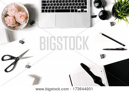 White office desk frame with laptop keyboard and supplies. Laptop, notebook, pen, roses, sunglasses, clips, pencil, plant, scissors, watch and office supplies on white background. Flat lay, top view, mockup