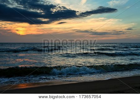 late in the evening on the sea, dark, beautiful landscape with sea waves and dark sky with bright orange stripes, cloudy, skyline, night, vespertine, extramural, afterdark