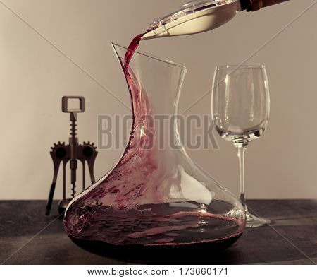 Pouring wine in carafe on gray table