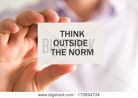 Businessman Holding A Card With Think Outside The Norm Message