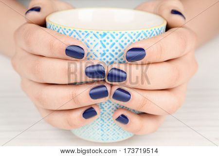 Nail art concept. Beautiful female hands with neat manicure holding cup, closeup
