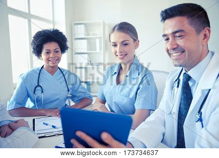 medical education, health care, people, technology and medicine concept - group of happy doctors with tablet pc computer meeting at medical office