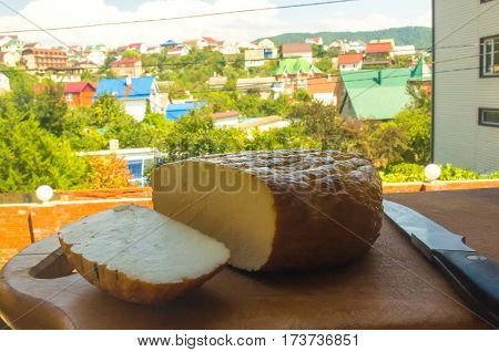 cut head of traditional Adygei cheese handmade with knife on wooden Board