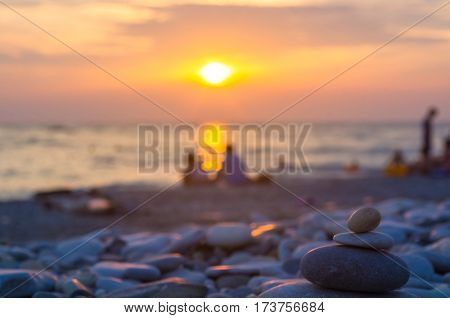 a couple and folded pyramid Zen pebble stones on the sea beach at sunset
