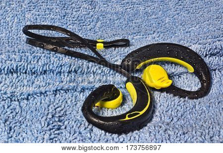 Waterproof headphones earphones yellow and black beaded with water. Headphones for running in the rain isolated on white background with light shadow and reflection.