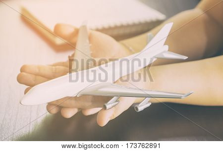 Child hands is holding a white airplane toy for Chidlren travel concept
