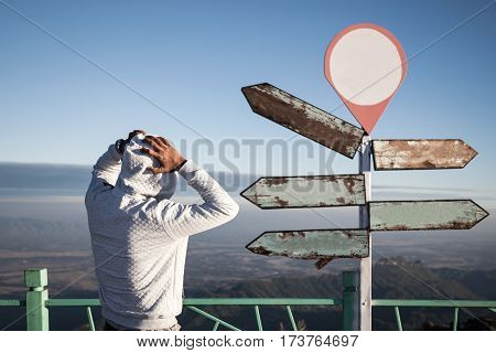astray man in doubt standing and confused in front of blank guidepost.