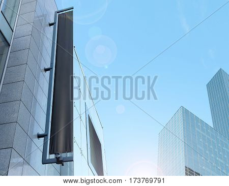 Blank black vertical banner on building facade, design mockup. Store flag mock up on the street. Outdoor banneret template on the side of the shop exterior. Sign hanging on the wall.