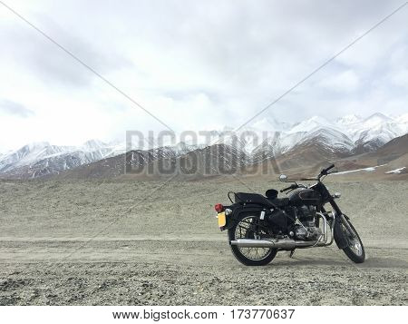 Motorcycle alone enduro traveler with suitcases standing on rocky plateau in cloudy weather on the background of endless mountain steppe Plateau Ukok Altai mountains Siberia Russia.