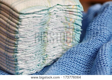 Stack of diapers or nappies on knitted blanket closeup