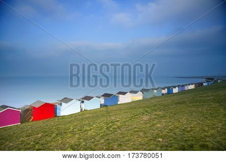 Row of colored beach huts with stormy blue sky on the beach of Tankerton near Whitstable in Kent, UK