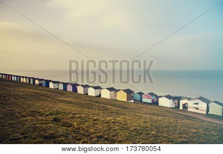 Row of colored beach huts with stormy blue sky on the beach of Tankerton near Whitstable in Kent, UK