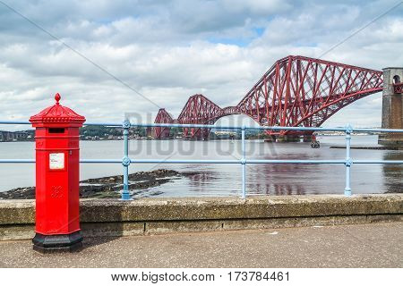 Red letterbox and Firth of Forth rail bridge in Edinburgh, Scotland UK