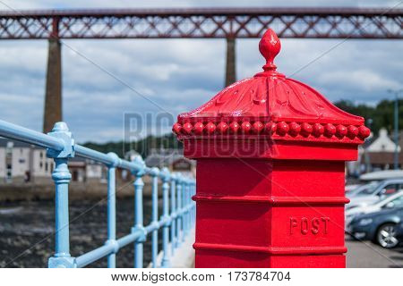 Red letterbox and Firth of Forth rail bridge in Edinburgh, Scotland UK