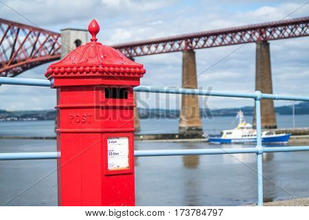 Red letterbox and Firth of Forth rail bridge in Edinburgh, Scotland UK