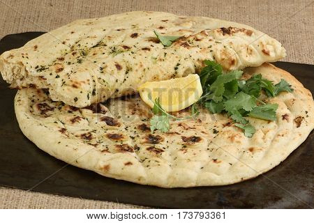 Fresh garlic and coriander naan garnished with lemon and coriander leaves