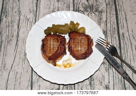 Deep fried pork steak with pickles and garlic on the plate.