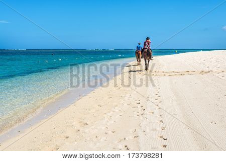 Le Morne Mauritius - December 11 2015: Couple riding on horseback along the sea on the Le Morne Beach one of the finest beaches in Mauritius and the site of many tourism facilities.