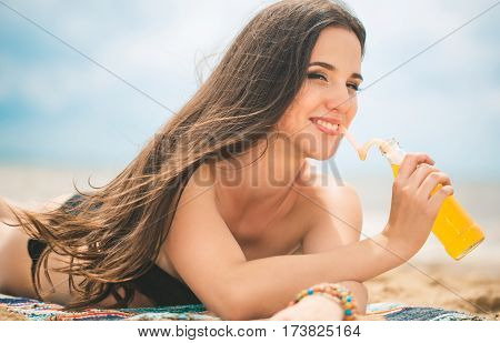 Beach woman drinking cold drink beverage having fun at beach party. Female babe in bikini enjoying orange water from glass boutle. summer concept