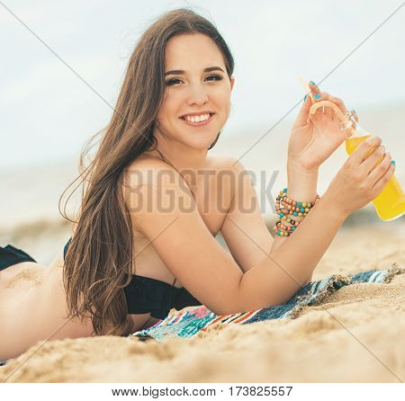 Beach woman drinking cold drink beverage having fun at beach party. Female babe in bikini enjoying orange water from glass boutle. summer concept