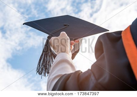Graduates of the UniversityOf graduates holding hats handed to the sky.