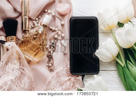 Phone Screen And Stylish Woman Lace Lingerie Jewelry And Perfume Present On Soft Fabric And Tulips O